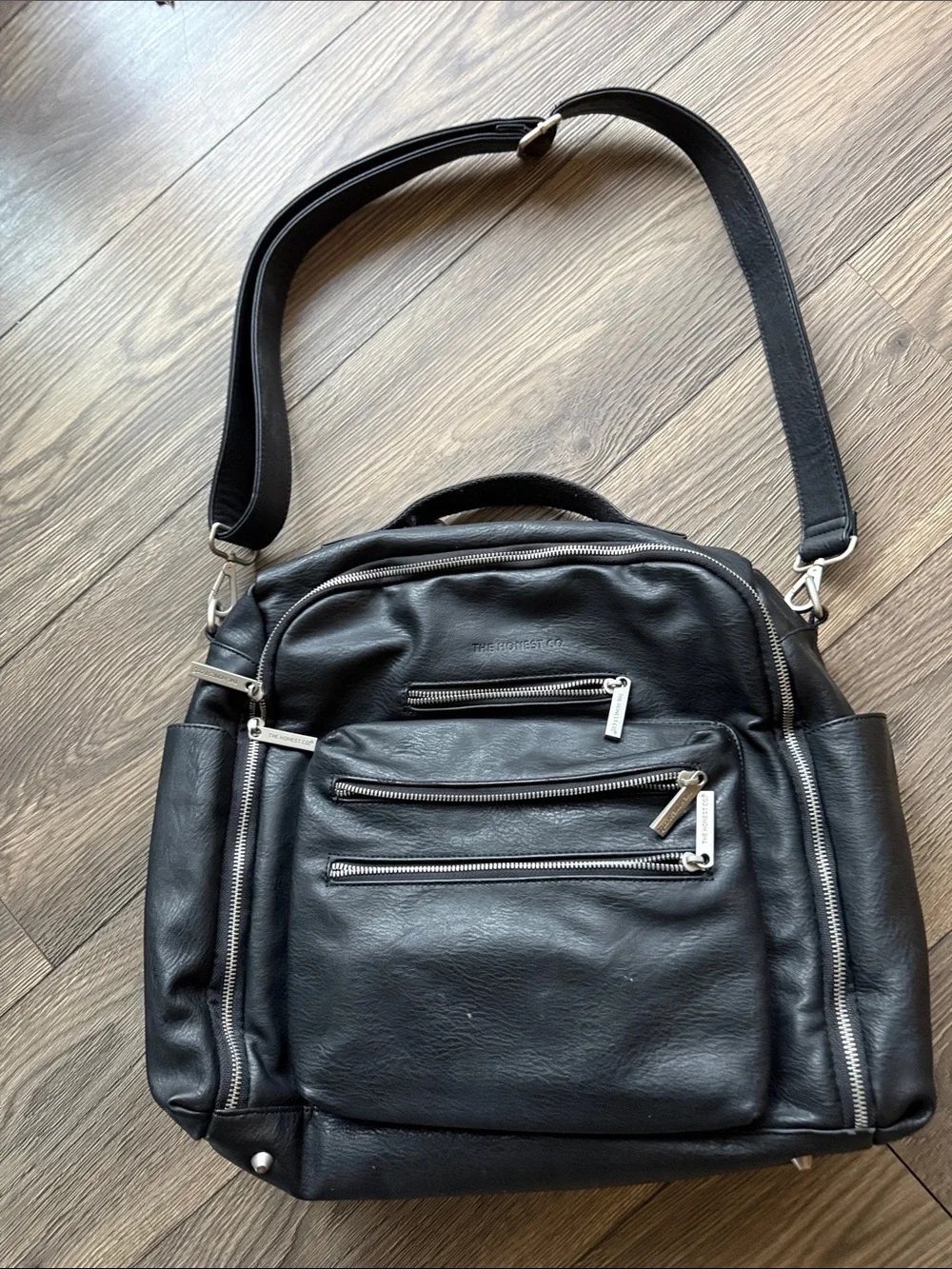 The Honest Company Black Vegan Leather Diaper Bag backpack model cross country